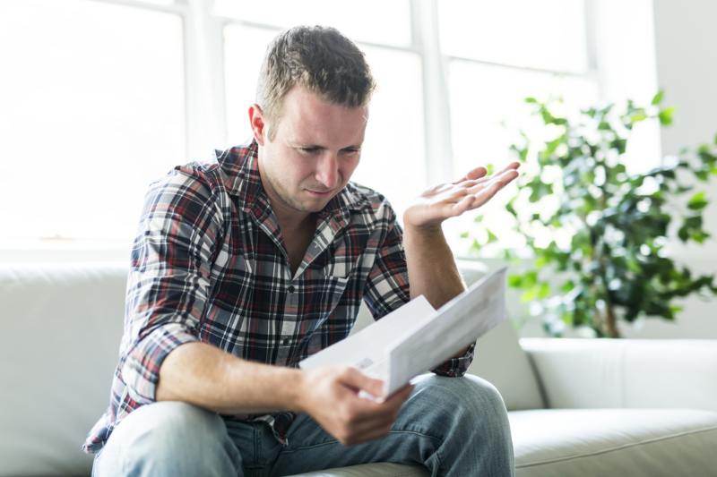 Shocked,Man,Holding,Some,Documents,On,Sofa,Livingroom